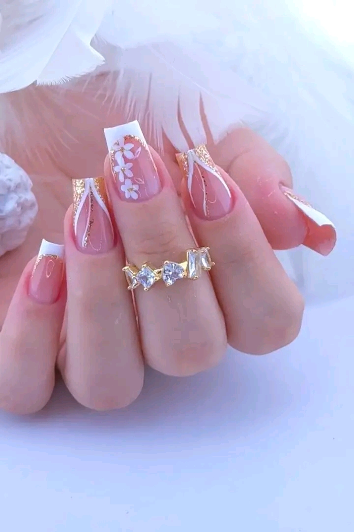 Diseño de uñas rosadas con flores y detalles dorados